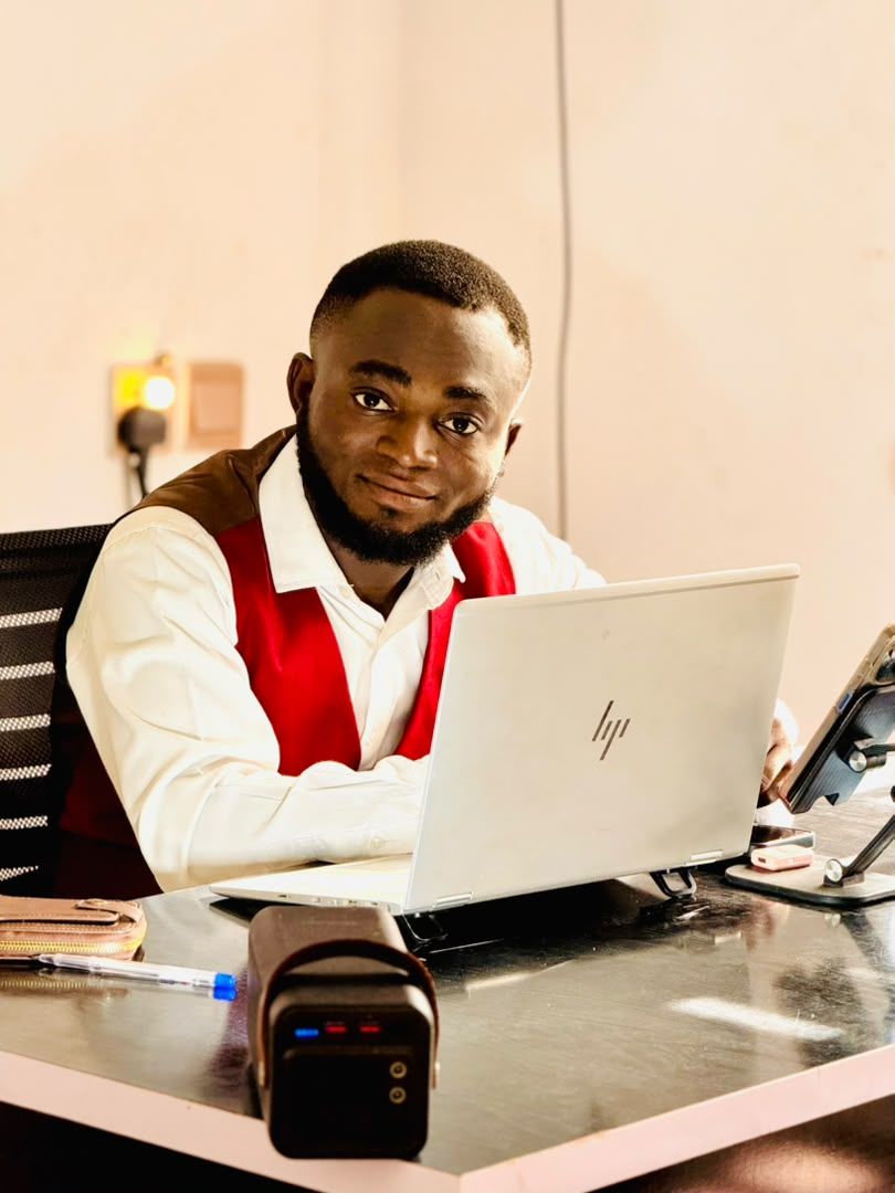 Taiwo Emma O smiling beside his laptop